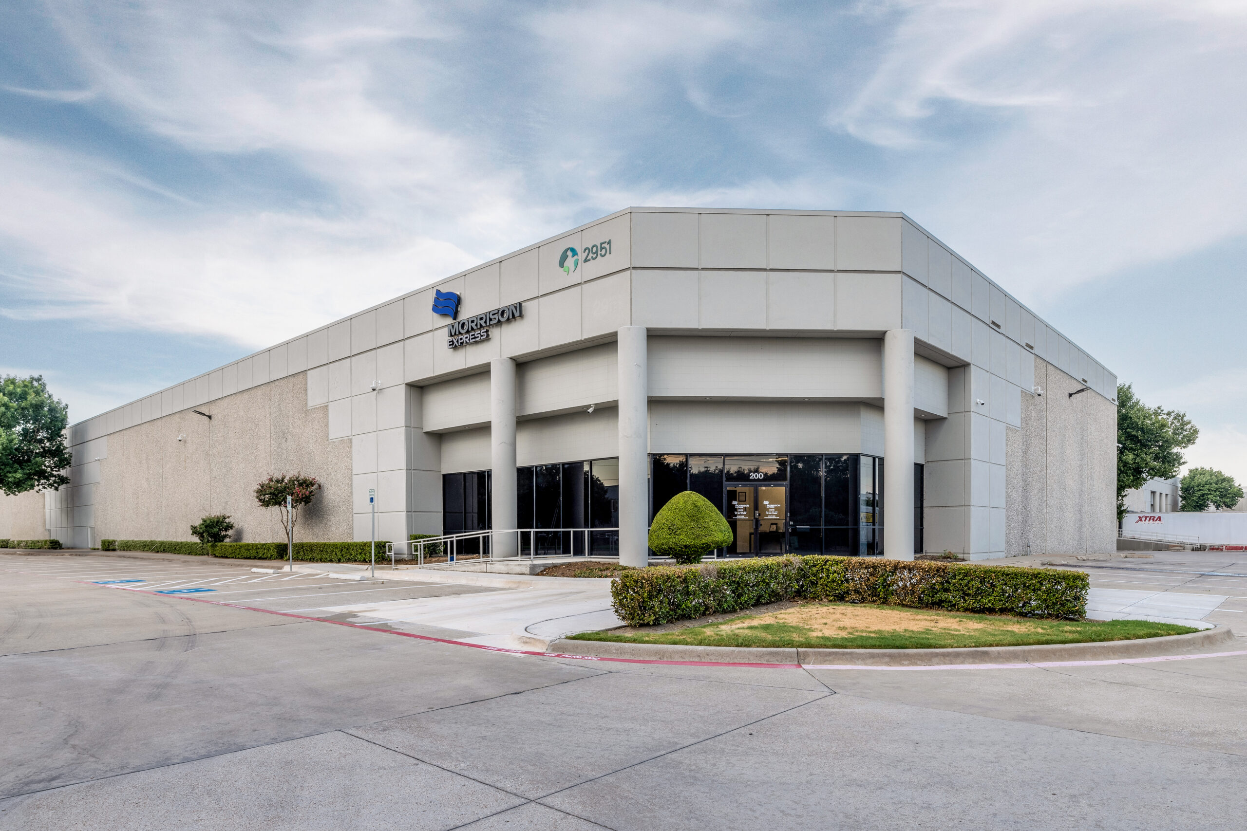 A large white office building of Morrison Express with parking space in front.