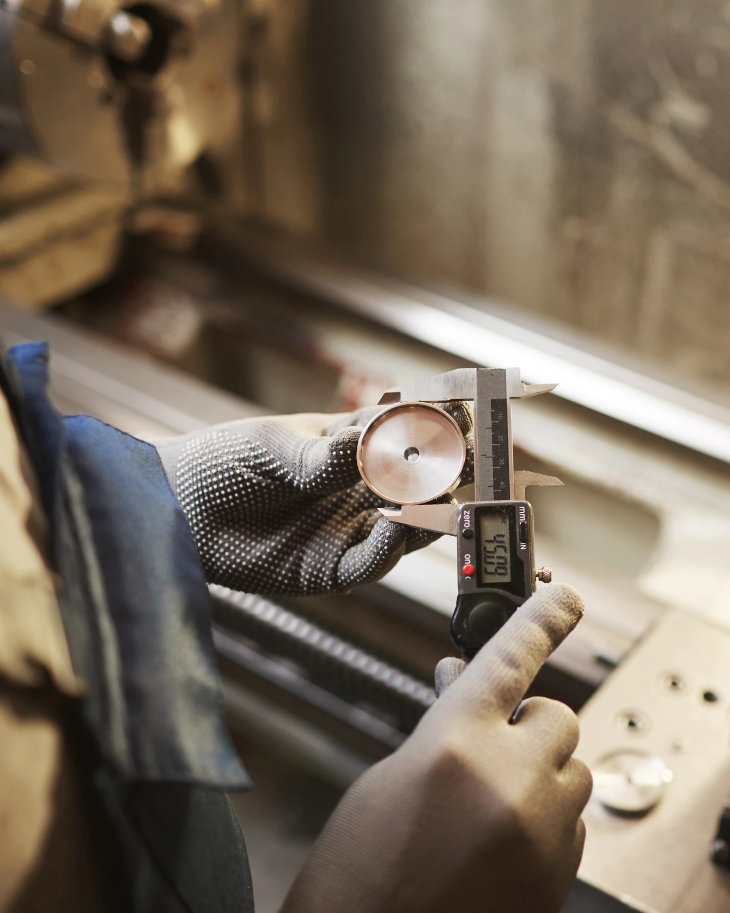 一名工业产业的工作人员使用测量仪器测量机械零件。