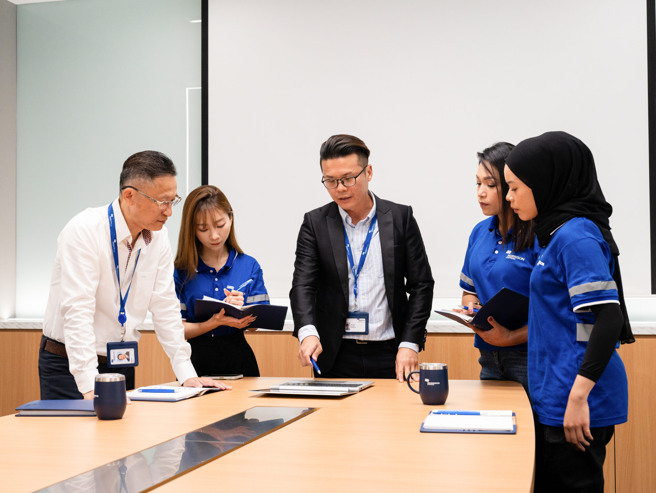 Morrison team members and manager gathered in a meeting room, collaborating on business objectives and professional development, symbolizing the essential mentorship support for success.