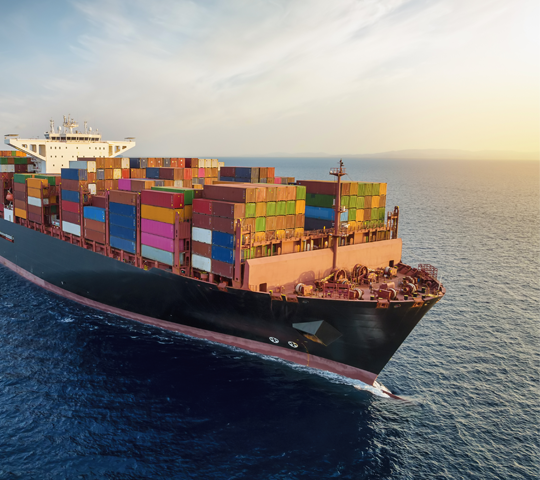 A cargo ship carrying cargo containers sailing across the ocean.