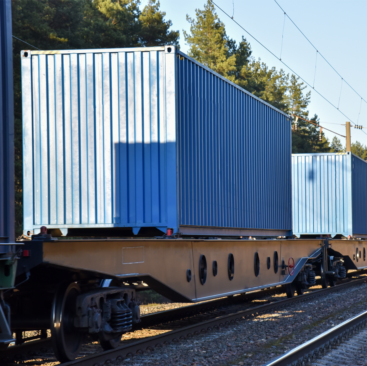 一列货运火车在铁轨上运载蓝色货柜。