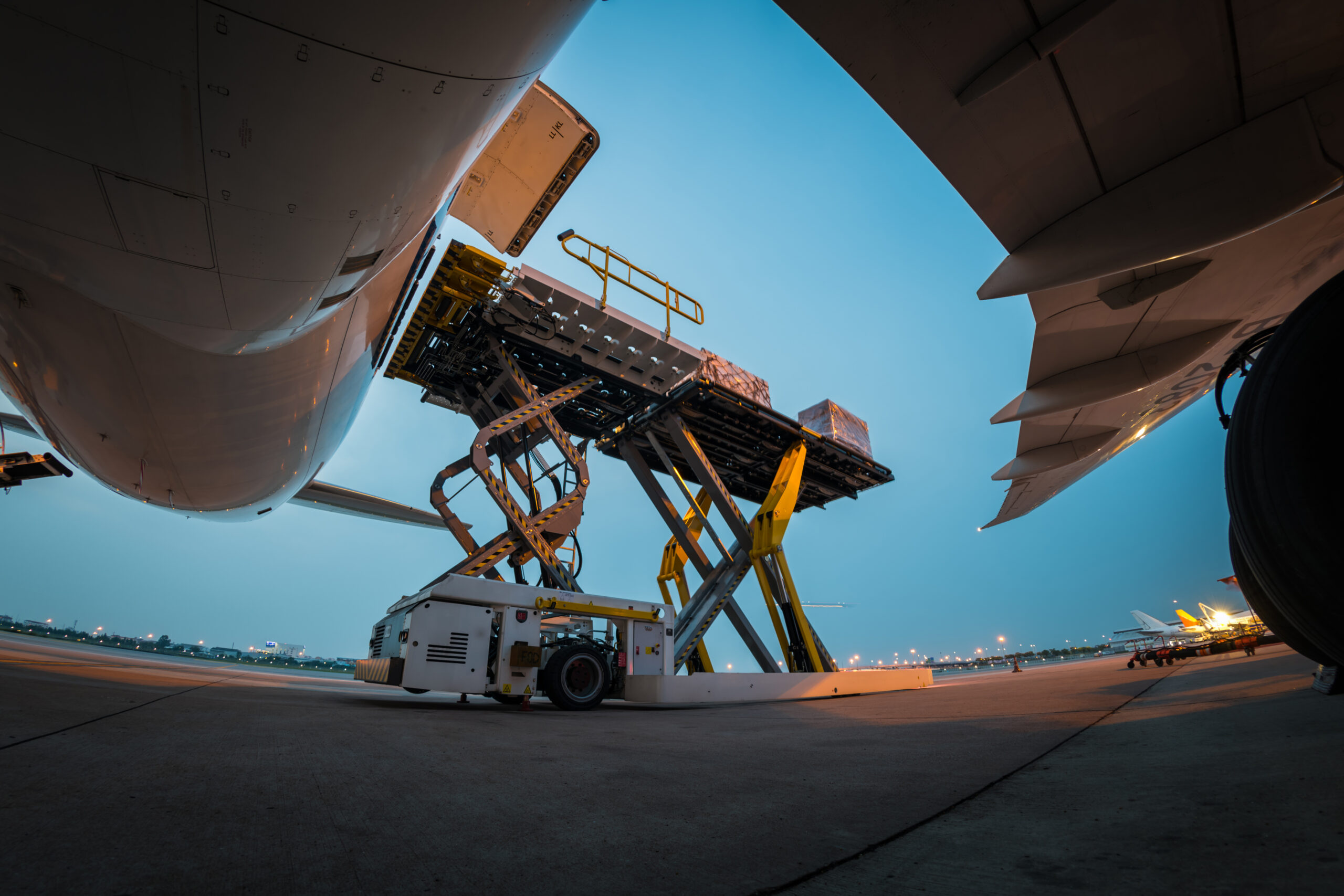 Cargo being loaded onto an airplane using hydraulic lift equipment.