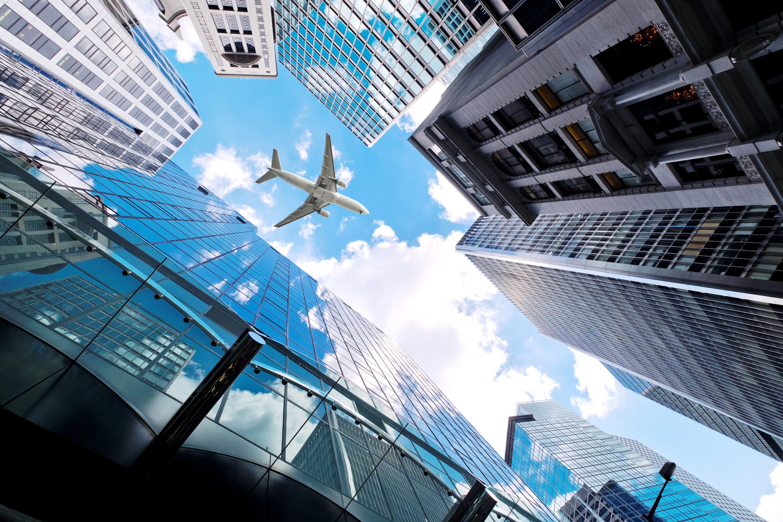 An aircraft soaring above urban  skyscrapers, indicative of our global presence.