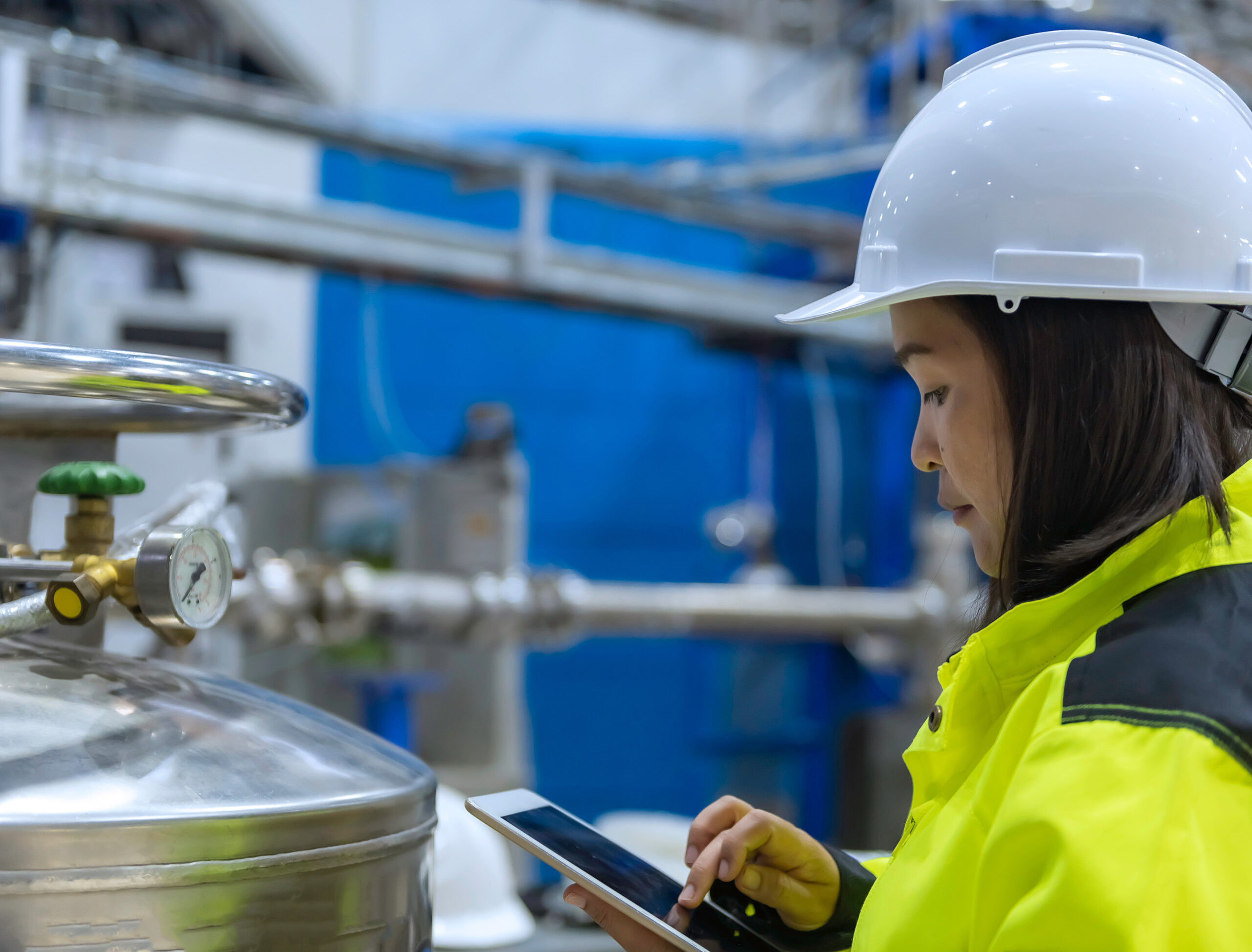 A logistics worker working with a tablet, monitoring chemical products in containers. 
