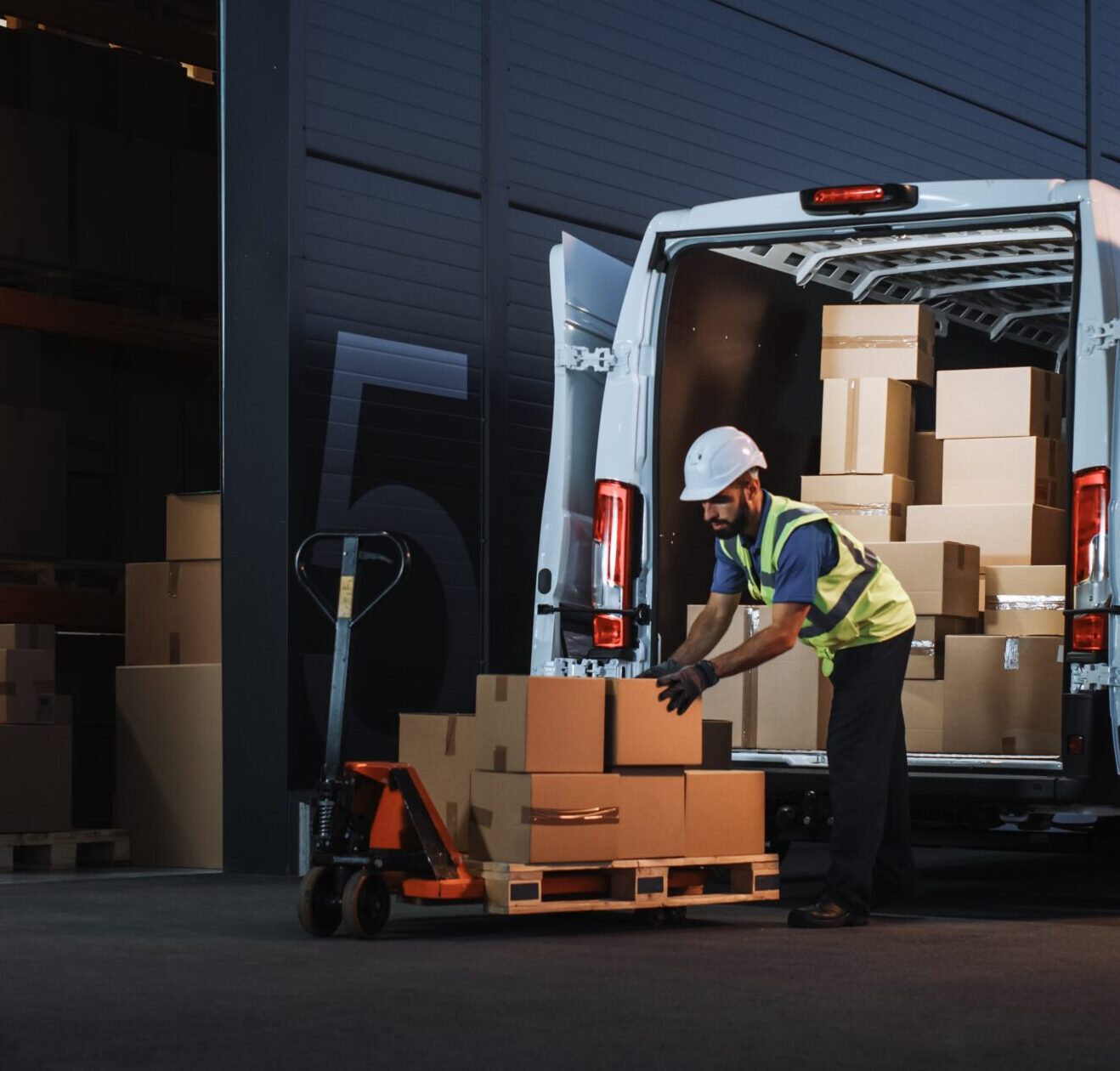 A warehouse worker unloading boxes from a van back to be moved back to the warehouse. 