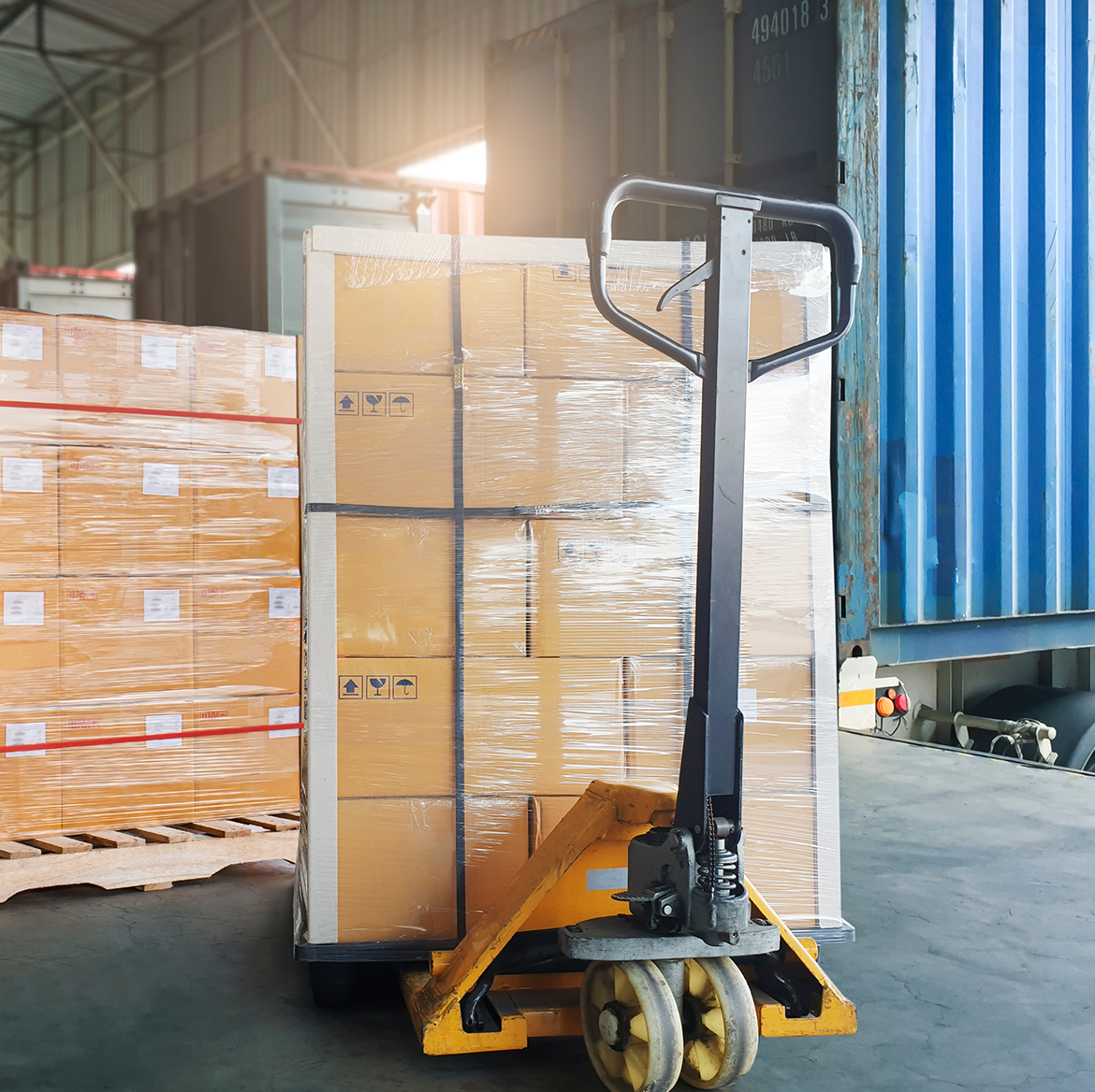 A cargo pallet on a pallet jack waiting to be loaded into a shipping container. 