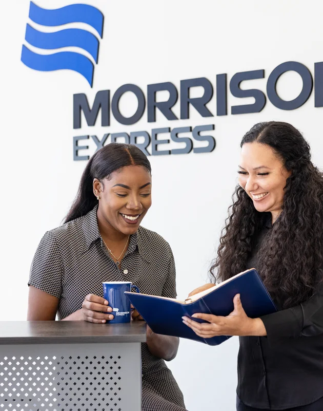 Two Morrison employees engaged in a discussion standing at the reception desk.
