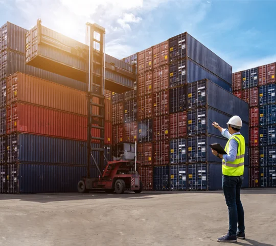  A customs broker, standing in a shipping container yard communicating on a walkie-talkie.