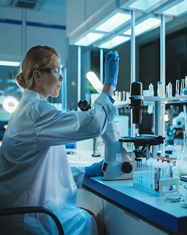 A healthcare scientist in a laboratory, examining a specimen.