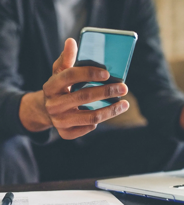 A business professional holding a smartphone in his right hand. 