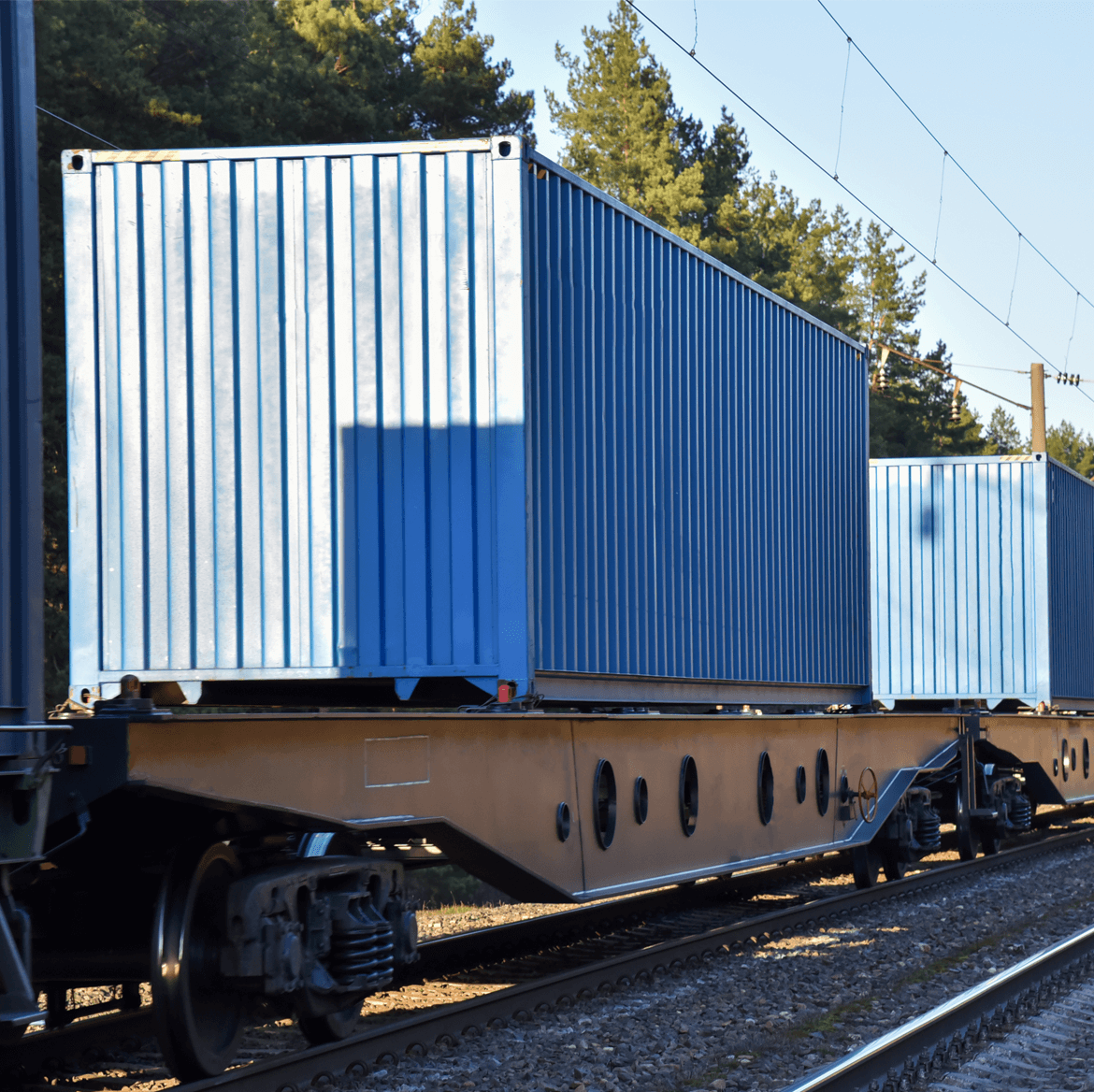 A train carrying blue cargo containers on its journey.