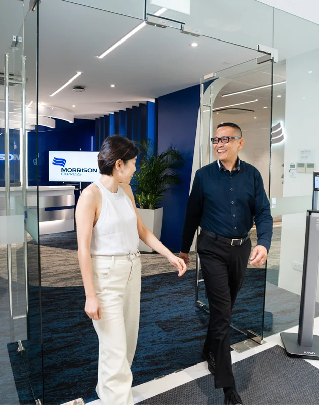 Two Morrison employees engaged in a discussion while walking out of a Morrison Express office. 